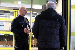 Na zdjęciu umundurowany policjant rozmawiający z seniorem