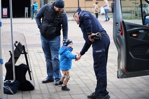 Na zdjęciu umundurowany policjant podający dłoń chłopcu