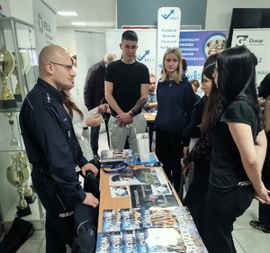 Na zdjęciu umundurowany policjant przy stoisku na IV Wiosennych Targach Pracy