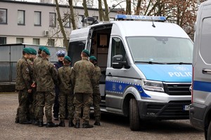 Na zdjęciu policjant ruchu drogowego oraz uczniowie klasy mundurowej stojący obok radiowozu