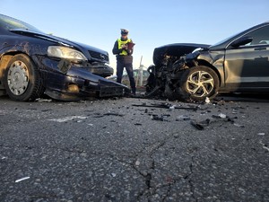 Na zdjęciu policjant oraz uszkodzone w zdarzeniu drogowym pojazdy