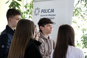 Na zdjęciu uczniowie biorący udział w dniu otwartym szkoły. W tle baner Komendy Miejskiej Policji w Tychach.