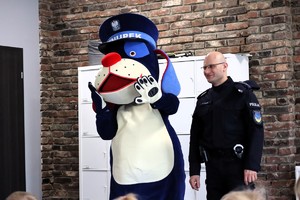 Na zdjęciu umundurowany policjant z policyjną maskotką Sznupkiem