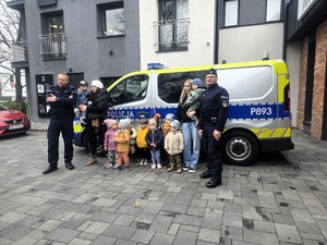 Na zdjęciu umundurowani policjanci z oraz grupa dzieci obok radiowozu