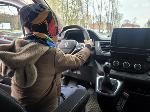 Na zdjęciu chłopiec siedzący za kierownicą radiowozu.
