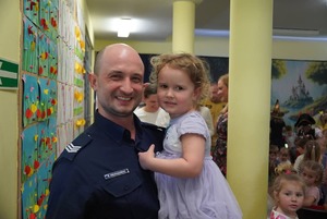 Na zdjęciu umundurowany policjant trzymający dziecko na rękach