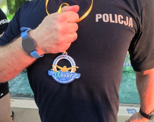 Na zdjęciu policjant trzymający pamiątkowy medal
