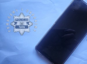Na zdjęciu telefon i logo Komendy Miejskiej Policji w Tychach