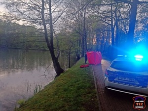 Na zdjęciu rozłożony obok stawu parawan. W tle radiowóz Policji