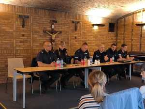 Na zdjęciu policjanci oraz funkcjonariusze straży miejskiej siedzący przy stole podczas debaty