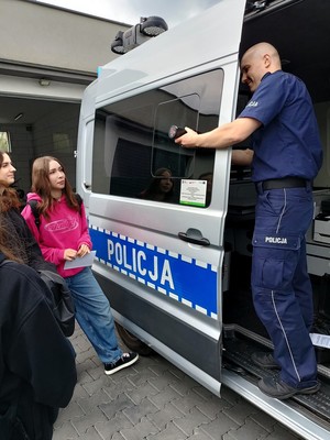 Na zdjęciu uczniowie oraz policjant przy radiowozie.
