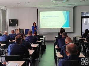 Umundurowani policjanci oraz kobieta prowadząca wykład podczas szkolenia