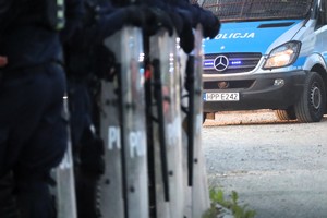 Na zdjęciu tarcze policjantów z oddziałów prewencji. W tle radiowóz.