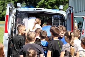 Na zdjęciu dzieci obok radiowozu policyjnego