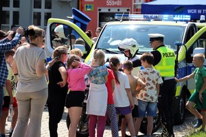 Na zdjęciu umundurowany policjant oraz radiowóz podczas rodzinnego pikniku