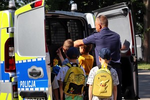 Na zdjęciu policjant i dzieci przy radiowozie