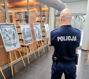 Na zdjęciu policjant przy plakatach