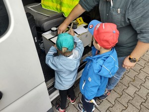 Na zdjęciu dzieci obok radiowozu ze stanowiskiem do pobierania linii papilarnych