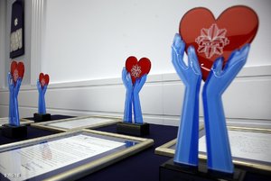 Statuetki konkursu „Policjant, który mi pomógł”-niebieskie dłonie trzymające czerwone serce