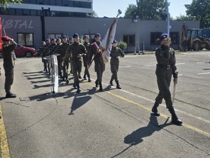 Uczniowie klasy mundurowej maszerujący w kompanii honorowej
