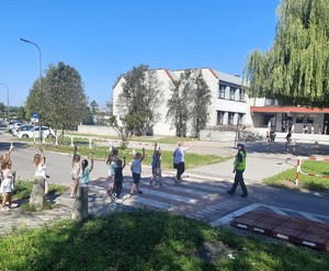 Na zdjęciu policjantka obok przejścia dla pieszych. Na przejściu dzieci