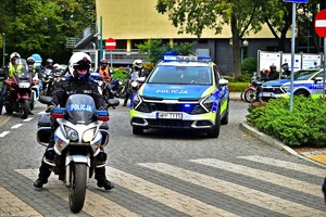 Na zdjęciu policjant na motocyklu, radiowóz oraz motocykliści