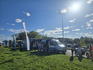 kolorowe zdjęcie przedstawiające policjantów przy radiowozie i motocyklu policyjnym wraz z dziećmi i ich opiekunami