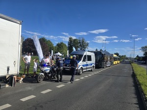 kolorowe zdjęcie przedstawiające policjantów przy radiowozie i motocyklu policyjnym wraz z dziećmi i ich opiekunami