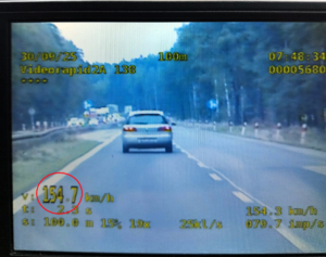 kolorowe zdjęcie ekranu video-rejestratora na którym widać fragment jezdni, pojazd, znak drogowy 70 km/h oraz parametry prędkości i odległości