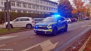 kolorowe zdjęcie oznakowane radiowozu z włączonymi sygnałami świetlnymi podczas eskorty