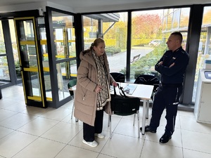 kolorowe zdjęcie umundurowanego funkcjonariusza prowadzącego rozmowę z kobietą.