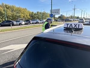 Kolorowe zdjęcie umundurowanej funkcjonariuszki policji przeprowadzających kontrolę pojazdu TAXI.