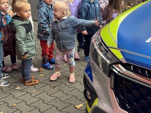 kolorowe zdjęcie dzieci na tle oznakowanego radiowozu