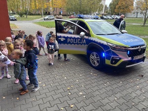 kolorowe zdjęcie dzieci w radiowozie oraz w jego pobliżu