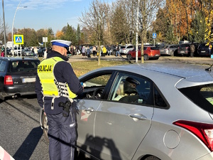 Kolorowe zdjęcie policjantów ruchu drogowego przeprowadzający badanie stanu trzeźwości kierujących samochodami.