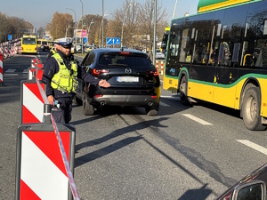 Kolorowe zdjęcie policjantów ruchu drogowego przeprowadzający badanie stanu trzeźwości kierujących samochodami.