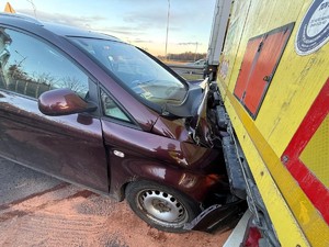 Kolorowe zdjęcie samochodu osobowego, którego przód wepchnięty jest pod tylną część naczepy ciężarowej.