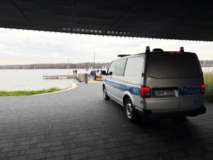 Kolorowe zdjęcie oznakowanego radiowozu zaparkowanego pod mariną.