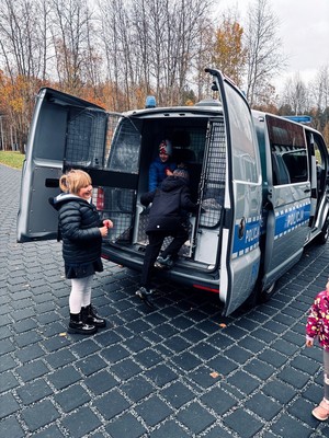 Kolorowe zdjęcie oznakowanego radiowozu oraz dzieci.