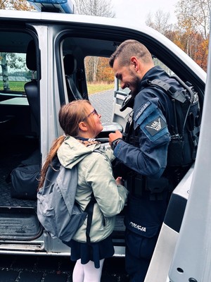Kolorowe zdjęcie policjanta rozmawiającego z dziewczynką.