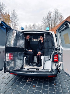 Kolorowe zdjęcie kobiety oraz mężczyzny siedzących w radiowozie.