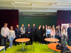 Kolorowe zdjęcie umundurowanych policjantów stojących wraz z młodzieżą.