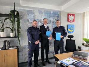 Kolorowe zdjęcie Prezydenta Miasta Tychy, Komendanta Komendy Miejskiej Policji w Tychach oraz Komendanta Straży Miejskiej w Tychach, stojących na tle ściany biura