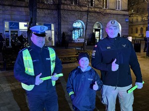 Kolorowe zdjęcie umundurowanego policjanta oraz strażaka pozujący do zdjęcia z chłopczykiem