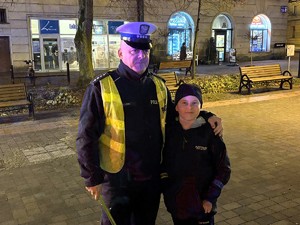 Kolorowe zdjęcie na którym widać umundurowanego policjanta pozującego do zdjęcia wraz z chłopcem.