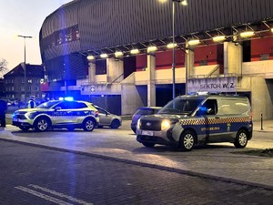 Kolorowe zdjęcie radiowozu policji oraz radiowozu straży miejskiej na tle stadionu miejskiego  w Tychach.