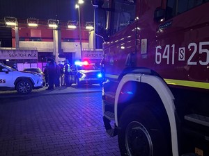 Kolorowe zdjęcie radiowozu policji, wozu strażackiego oraz radiowozu straży miejskiej na tle stadionu miejskiego  w Tychach.