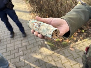 kolorowe zdjęcie łuski pocisku artyleryjskiego trzymanego w ręce przez żołnierza.