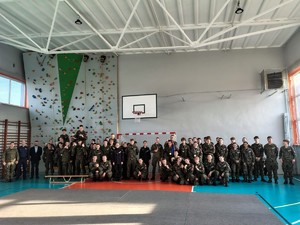 Kolorowe zdjęcie uczestników turnieju/konkursu musztry stojących wspólnie z członkami komisji.