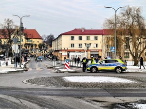 Kolorowe zdjęcie oznakowanych radiowozów Policji oraz umundurowanych policjantów na tle osób biorących udział w orszaku.